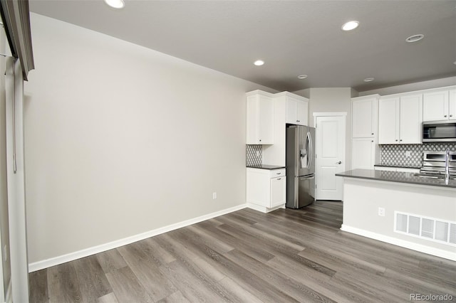 kitchen with backsplash, dark hardwood / wood-style flooring, white cabinets, and stainless steel appliances