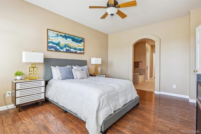 bedroom with arched walkways, wood finished floors, and baseboards