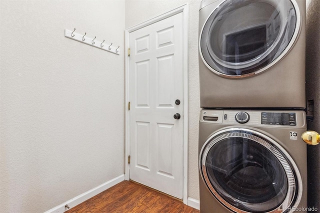 laundry room with estacked washer and dryer, dark wood-style floors, and baseboards