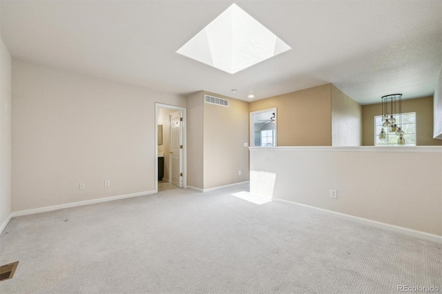 carpeted spare room featuring baseboards and a skylight