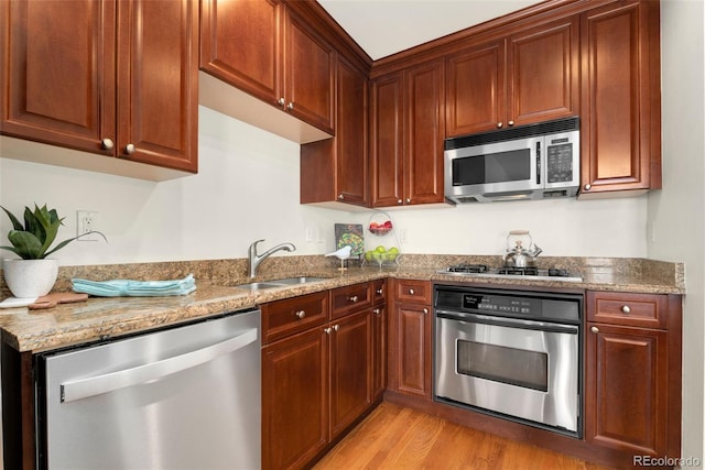 1827 N Grant St Unit 604, Denver, CO 80203 - kitchen with stainless steel appliances, a sink, light wood finished floors, and light stone countertops