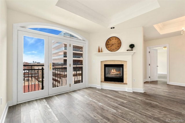 1827 N Grant St Unit 604, Denver, CO 80203 - unfurnished living room featuring a tray ceiling, wood finished floors, a glass covered fireplace, baseboards, and crown molding