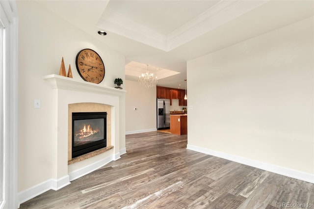 1827 N Grant St Unit 604, Denver, CO 80203 - unfurnished living room featuring a raised ceiling, wood finished floors, a chandelier, a glass covered fireplace, and crown molding
