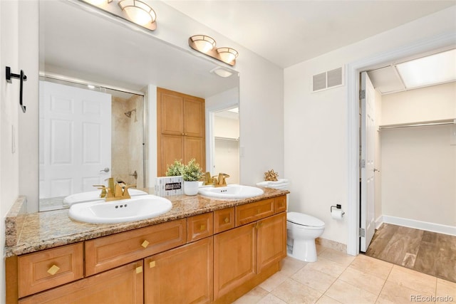1827 N Grant St Unit 604, Denver, CO 80203 - bathroom featuring double vanity, a tile shower, toilet, tile patterned flooring, and a walk in closet