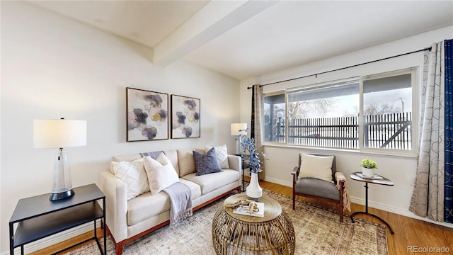 living room with beamed ceiling, wood finished floors, and baseboards