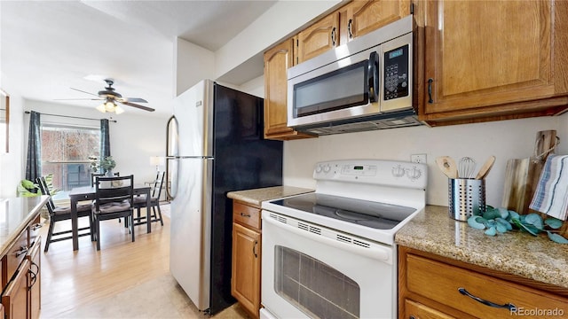 kitchen featuring ceiling fan, stainless steel appliances, light stone countertops, and brown cabinets