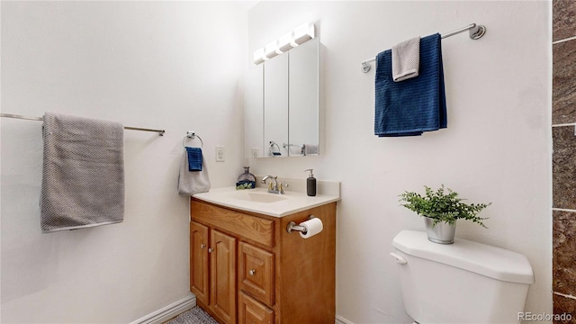 bathroom featuring toilet, vanity, and baseboards