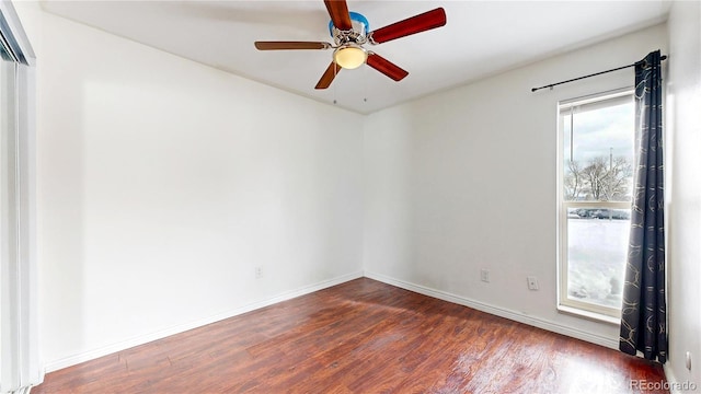 empty room featuring ceiling fan, dark wood finished floors, and baseboards