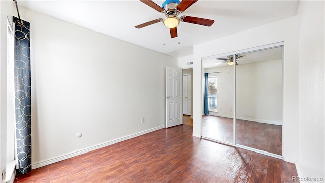 unfurnished bedroom with a closet, dark wood finished floors, baseboards, and ceiling fan