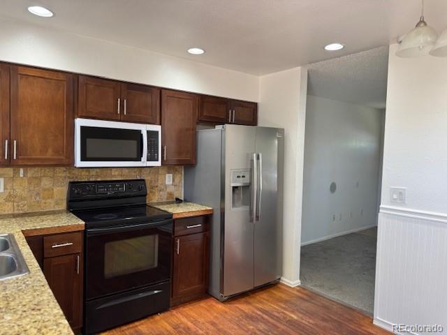 16753 E Ithaca Pl, Aurora, CO 80013 - kitchen featuring black / electric stove, white microwave, stainless steel fridge with ice dispenser, light countertops, and decorative backsplash