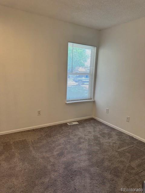 16753 E Ithaca Pl, Aurora, CO 80013 - unfurnished room with dark carpet and a textured ceiling