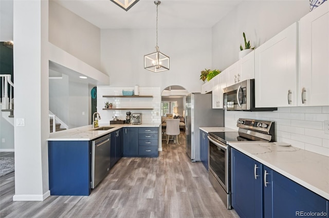 6468 S Forest St, Centennial, CO 80121 - kitchen featuring appliances with stainless steel finishes, blue cabinetry, light wood-style flooring, open shelves, and high vaulted ceiling