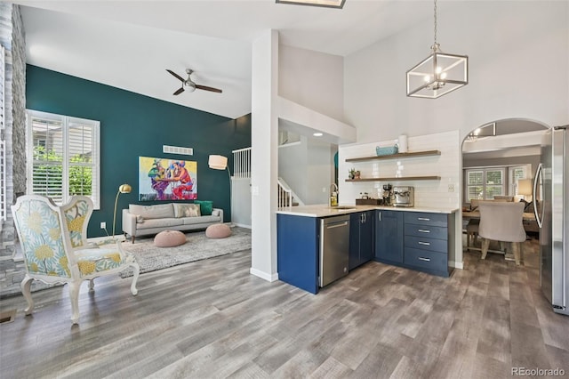6468 S Forest St, Centennial, CO 80121 - kitchen featuring appliances with stainless steel finishes, arched walkways, wood finished floors, high vaulted ceiling, and light countertops