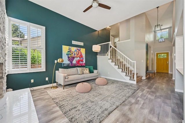 6468 S Forest St, Centennial, CO 80121 - living room featuring stairway, wood finished floors, ceiling fan, a high ceiling, and an accent wall