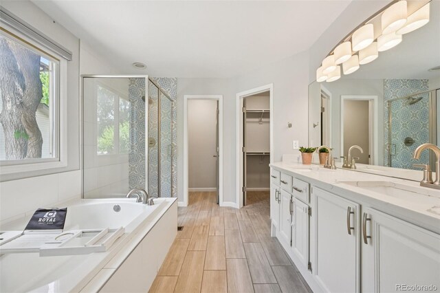 6468 S Forest St, Centennial, CO 80121 - full bathroom featuring a stall shower, a walk in closet, double vanity, a garden tub, and wood finished floors
