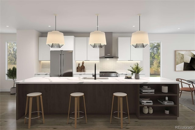 kitchen featuring a sink, white cabinetry, high quality fridge, wall chimney range hood, and range