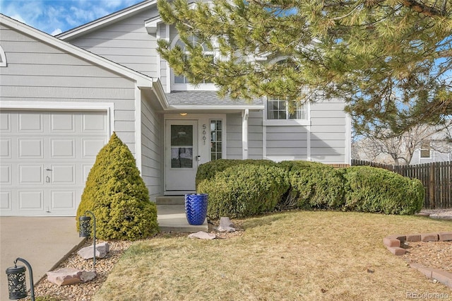 view of exterior entry with a garage, a yard, and fence