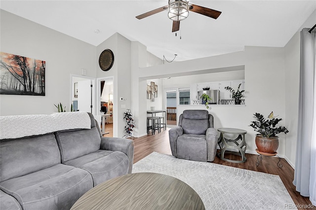 living room with dark wood-style floors, vaulted ceiling, baseboards, and ceiling fan