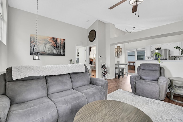 living area with a wealth of natural light, ceiling fan, baseboards, and wood finished floors