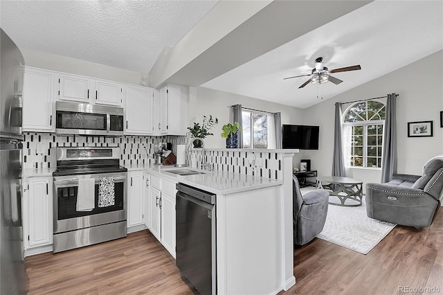 kitchen with open floor plan, stainless steel appliances, light countertops, and white cabinetry