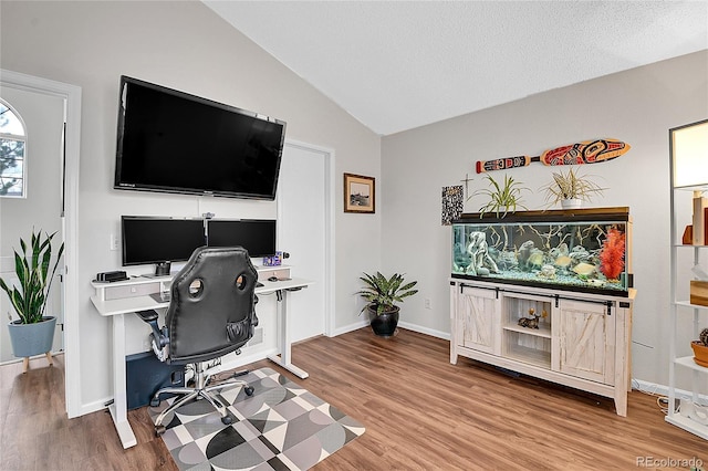 office space featuring lofted ceiling, a textured ceiling, baseboards, and wood finished floors