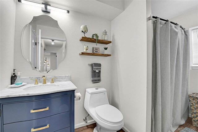 bathroom with toilet, wood finished floors, vanity, baseboards, and a shower with curtain