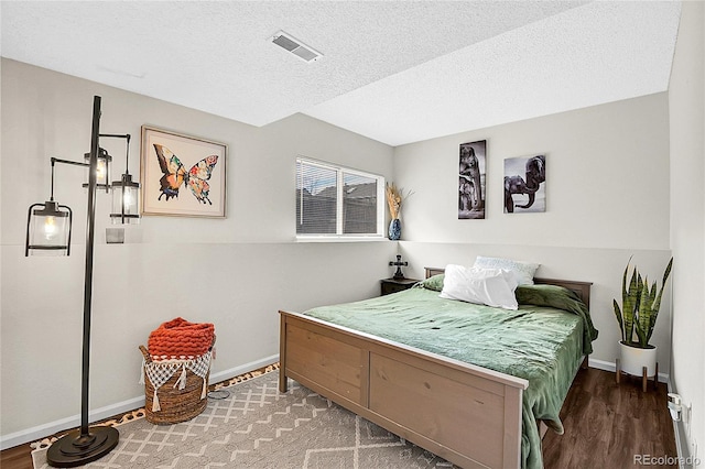 bedroom featuring a textured ceiling, dark wood-type flooring, visible vents, and baseboards