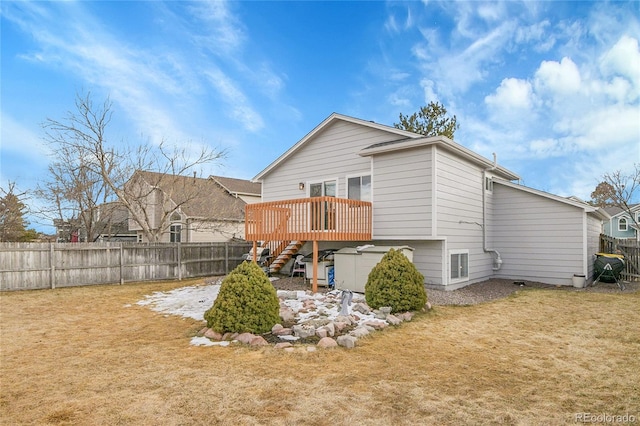 back of property with fence, a lawn, a wooden deck, and stairs