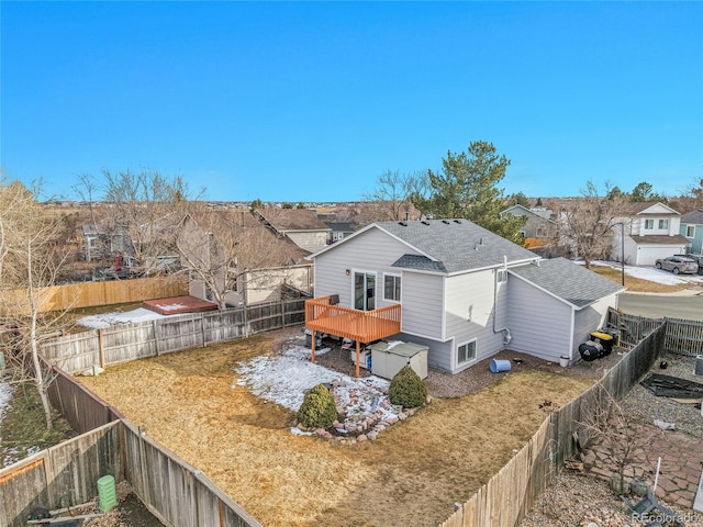 exterior space with a fenced backyard, a residential view, a deck, and roof with shingles