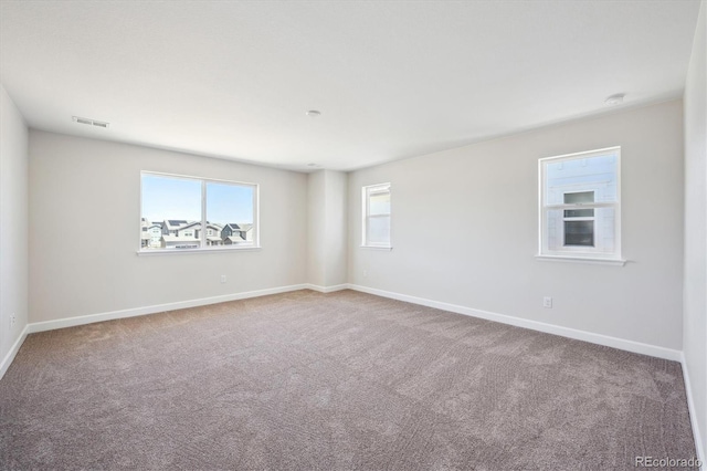 empty room featuring carpet, baseboards, and visible vents