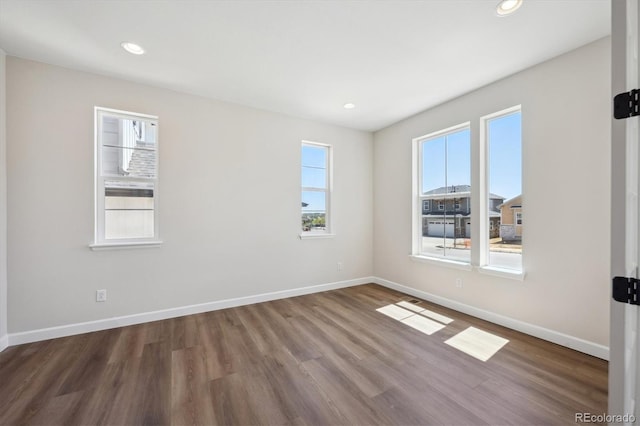 empty room with a wealth of natural light, baseboards, and wood finished floors