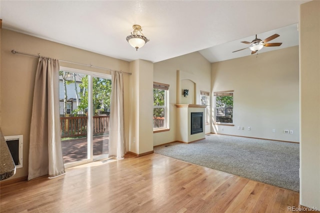1481 Box Prairie Cir, Loveland, CO 80538 - unfurnished living room featuring baseboards, a glass covered fireplace, wood finished floors, a ceiling fan, and vaulted ceiling