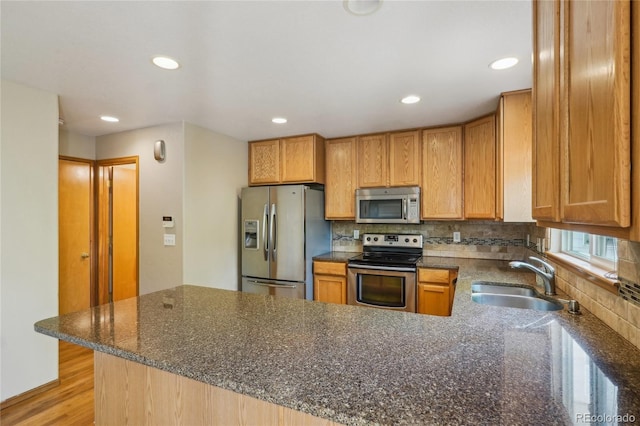 1481 Box Prairie Cir, Loveland, CO 80538 - kitchen with stainless steel appliances, a sink, a peninsula, decorative backsplash, and dark stone counters