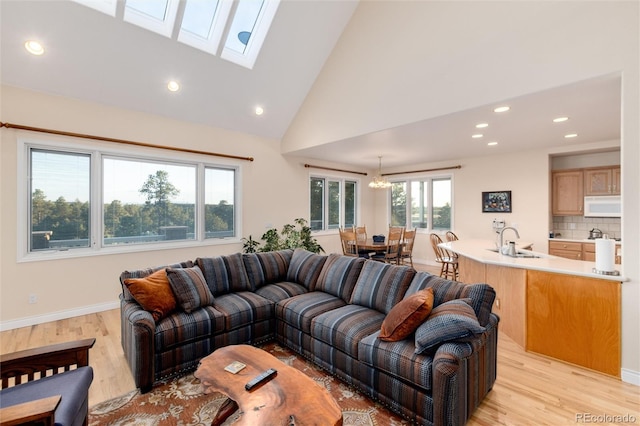 34274 Wolf Creek Trl, Kiowa, CO 80117 - living room featuring recessed lighting, light wood-type flooring, a chandelier, baseboards, and a skylight