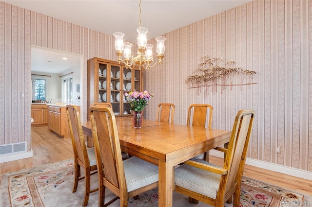 34274 Wolf Creek Trl, Kiowa, CO 80117 - dining room with wallpapered walls, light wood-style floors, a chandelier, and baseboards