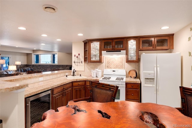 34274 Wolf Creek Trl, Kiowa, CO 80117 - kitchen with white appliances, beverage cooler, under cabinet range hood, a sink, and decorative backsplash