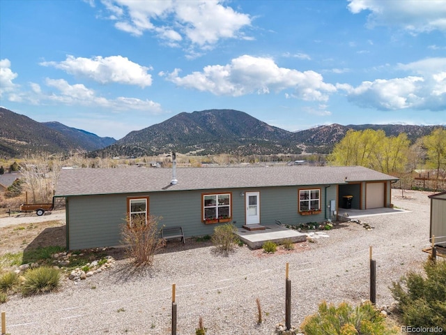 back of house featuring an attached garage, a mountain view, and driveway