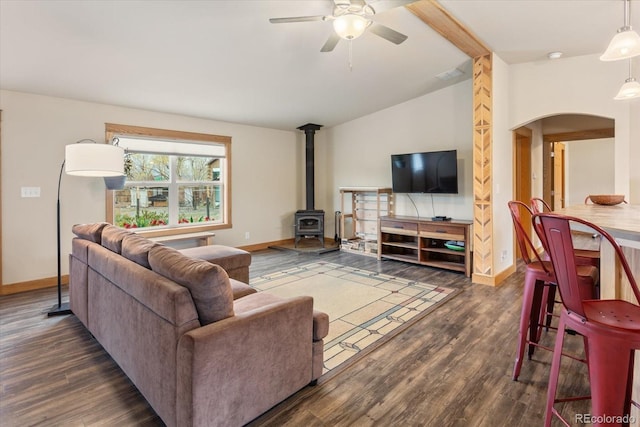 living room with arched walkways, ceiling fan, baseboards, and a wood stove