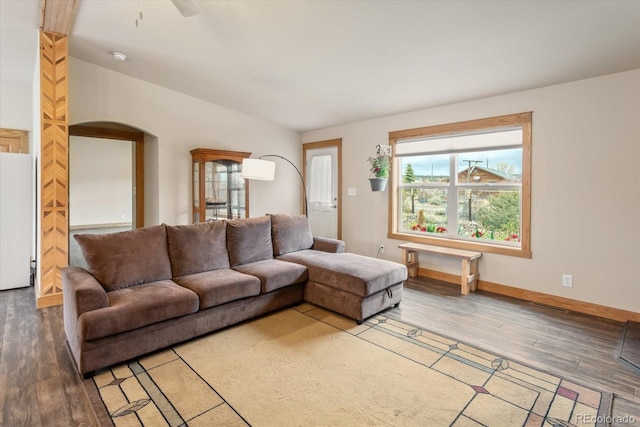 living room with arched walkways, baseboards, vaulted ceiling, and light wood-style floors