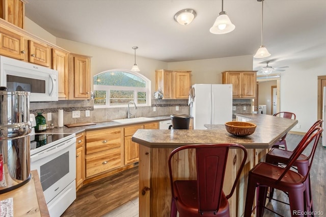kitchen with a sink, white appliances, dark wood-type flooring, backsplash, and a kitchen island