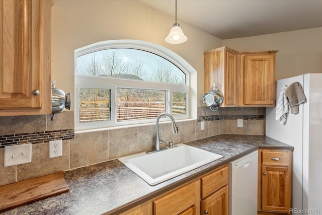 kitchen with a sink, dark countertops, white appliances, and tasteful backsplash
