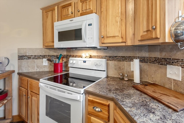 kitchen with white appliances, backsplash, and dark countertops