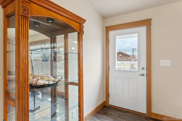 doorway with baseboards and wood finished floors