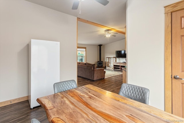dining room with a wood stove, dark wood finished floors, ceiling fan, and lofted ceiling