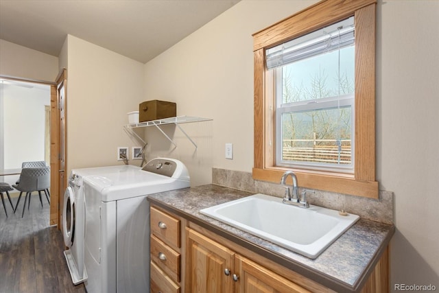 washroom with washing machine and clothes dryer, cabinet space, a sink, and dark wood-type flooring