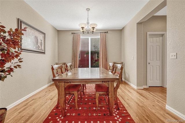 dining room featuring wood-type flooring, a notable chandelier, and a textured ceiling