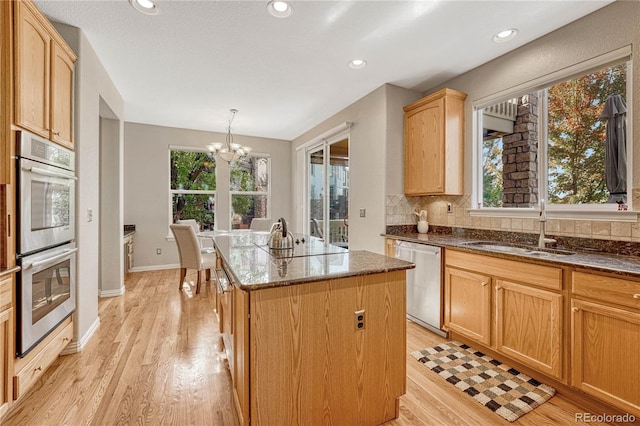 kitchen featuring a wealth of natural light, stainless steel appliances, decorative light fixtures, and a kitchen island