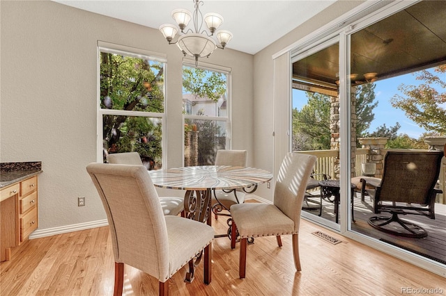 dining space with light hardwood / wood-style floors and an inviting chandelier