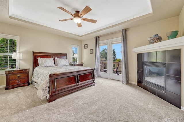 carpeted bedroom featuring a fireplace, access to outside, ceiling fan, and a raised ceiling