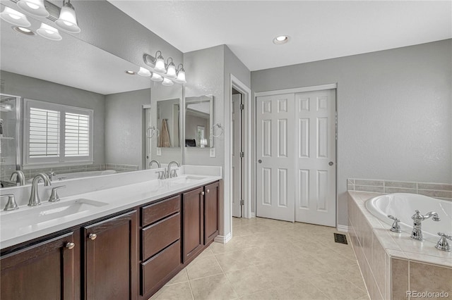 bathroom featuring tiled bath, tile patterned flooring, and vanity